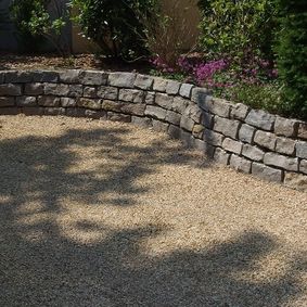 Natursteinmauer aus Muschelkalksteinen - Abdeckmaterial der Zufahrt: gelber Granit-Edelsplitt 8-11